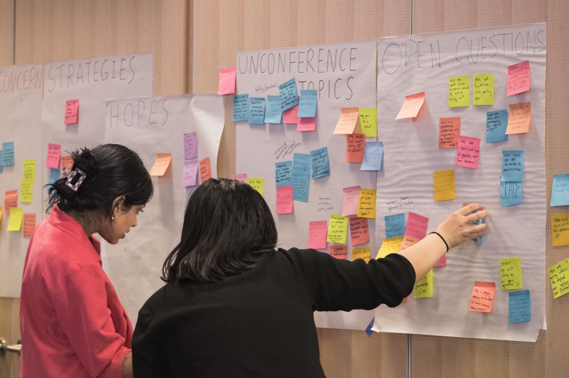 Workshop organizers cluster participants’ Post-it notes—their hopes, concerns, strategies, and questions—into shared themes that shape the unconference discussions.
